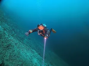 Taucher mit Lampe im Kreidesee Hemmoor während eines SDI Deep Diver Kurses in größerer Tiefe